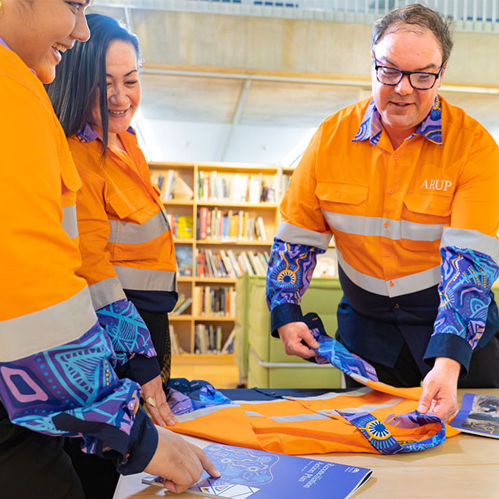 A group of people in matching orange shirts featuring Aboriginal artwork