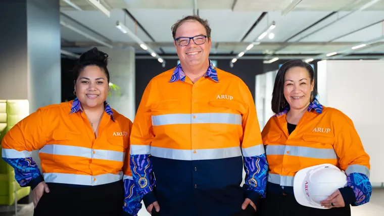 A group of people wearing high visibility, bright orange shirts with Arup logo and Aboriginal artwork