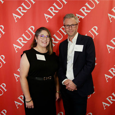 A man and woman standing in front of a red wall.