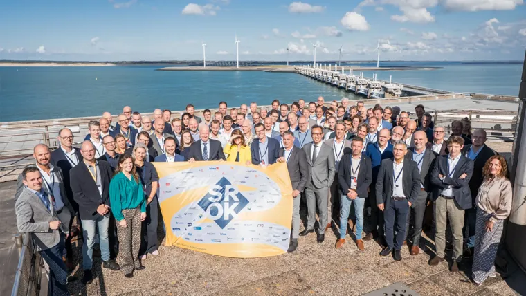 A group of people posing for a photo with a sign.