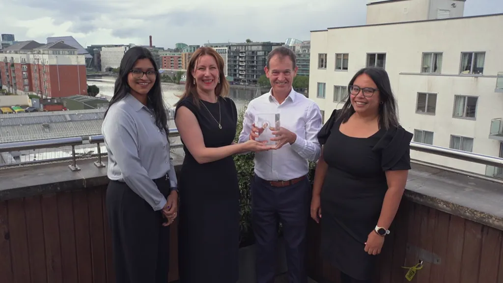 Four people on balcony in Arup's Dublin office holding the Engineers Ireland CPD Employer of the Year trophy.