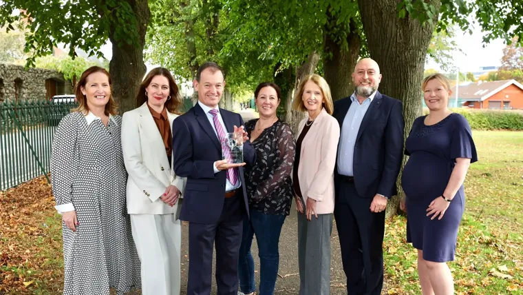 Members of the Arup team holding the Engineers Ireland CPD Employer of the Year trophy in a park with trees in the background.