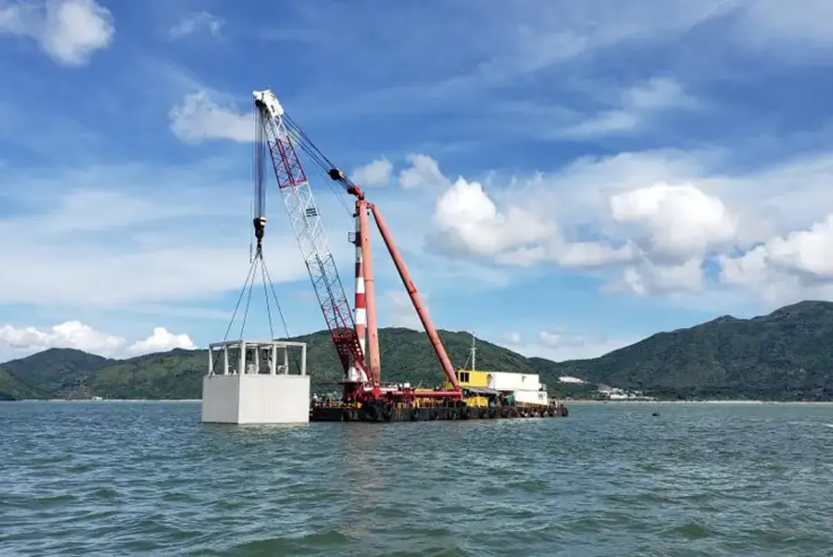 A large red and white crane on a dock in the water.