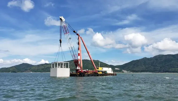 A large red and white crane on a dock in the water.