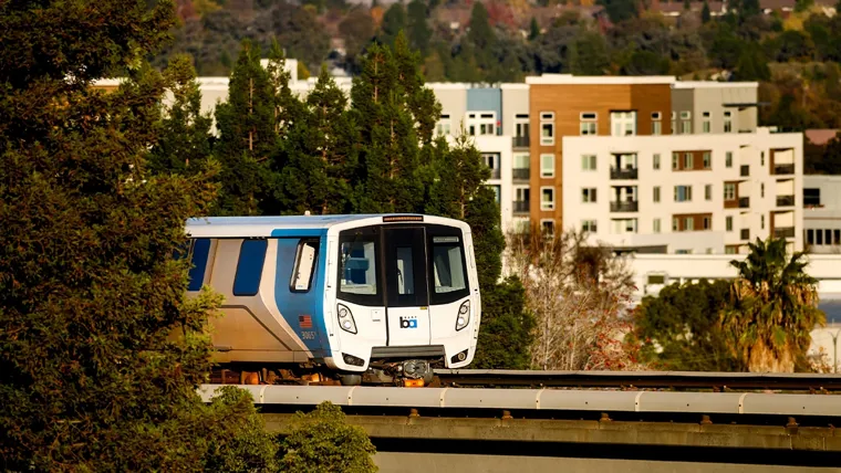 A train on the railway tracks with buildings and trees in background