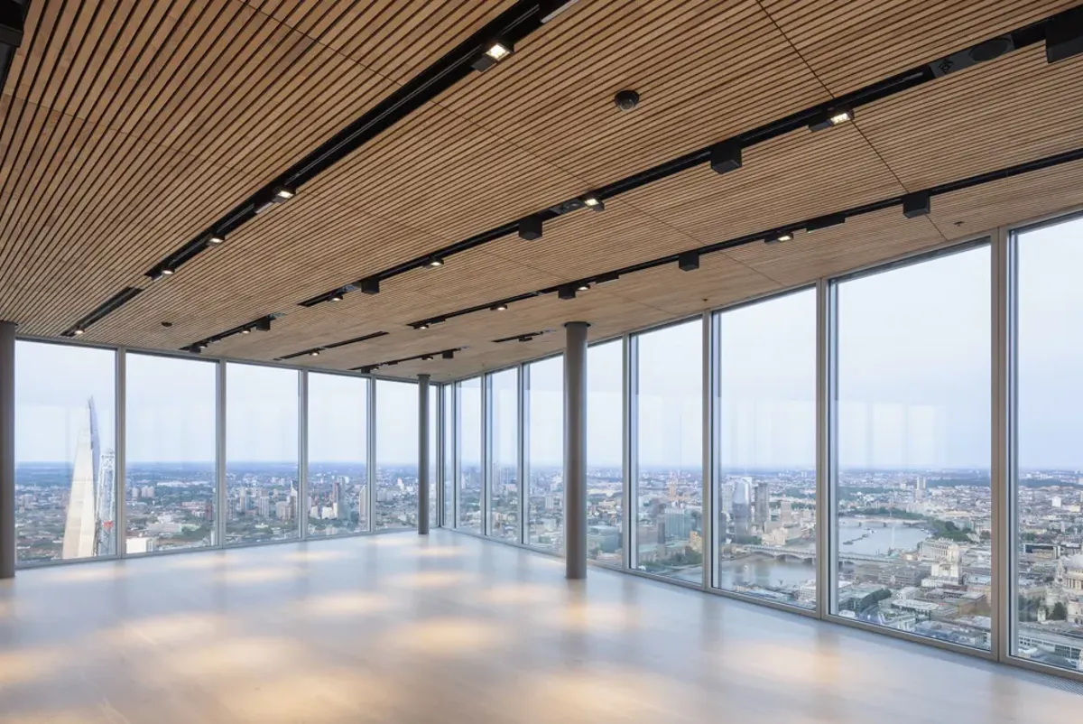 A room with large windows and a city below.