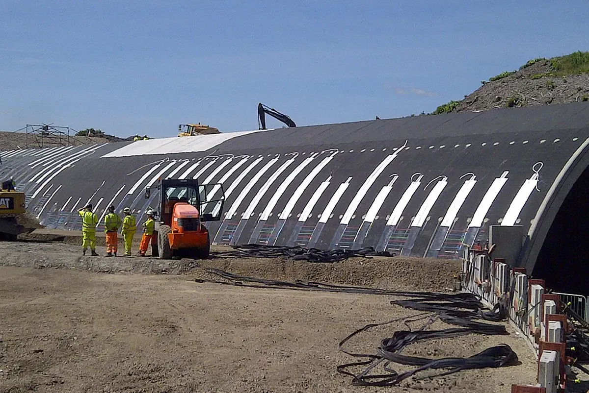 A group of men standing next to a large pipe.