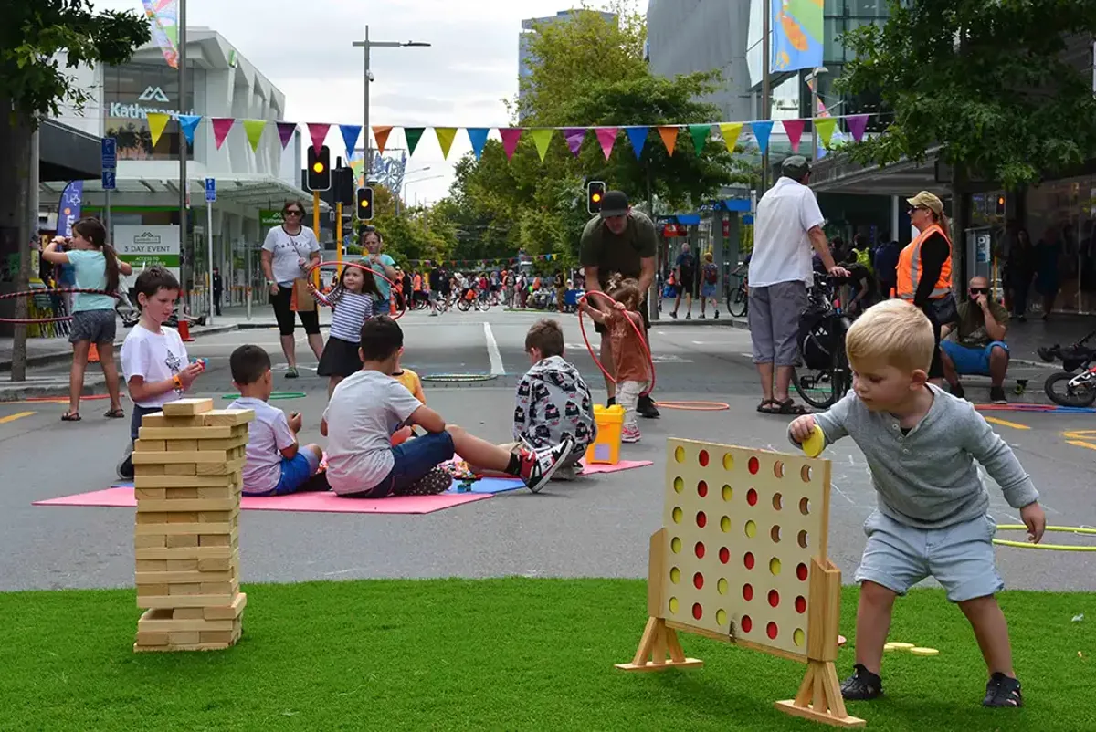 Young children playing with games in a city street closed off to traffic