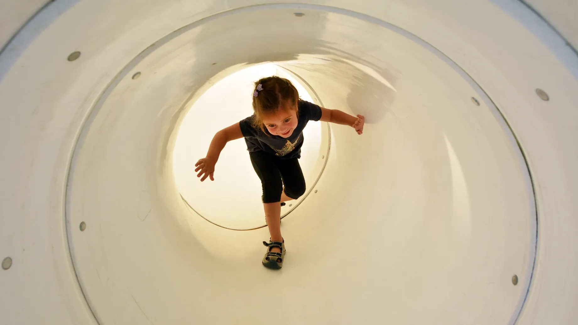 Young child playing inside a large white plastic tunnel