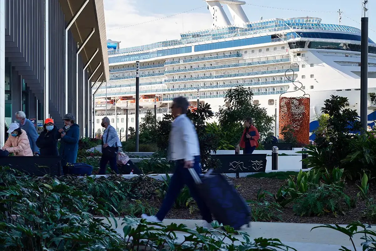 Passengers walking into Brisbane International Cruise Terminal with large cruise ship in background
