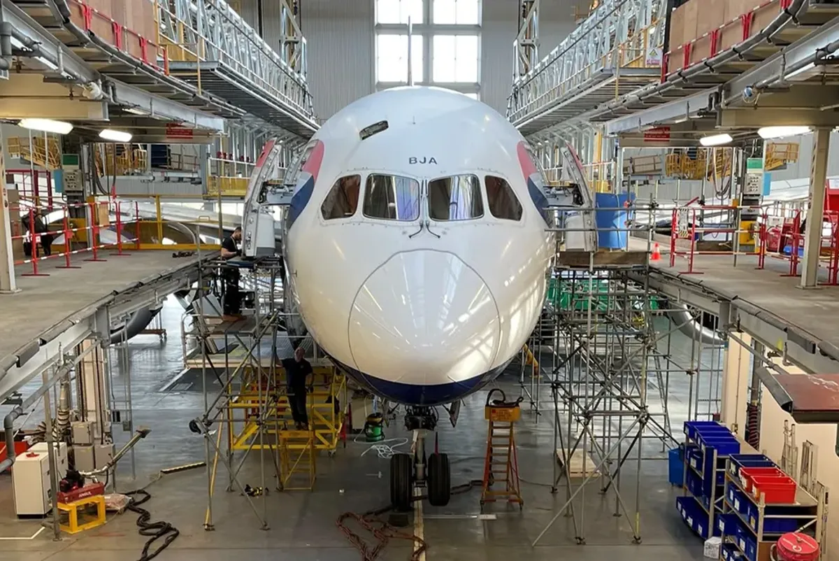 A large white airplane in a warehouse.
