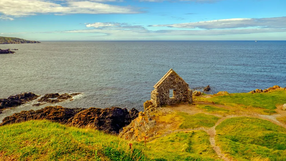 A stone building on a hill by the water.