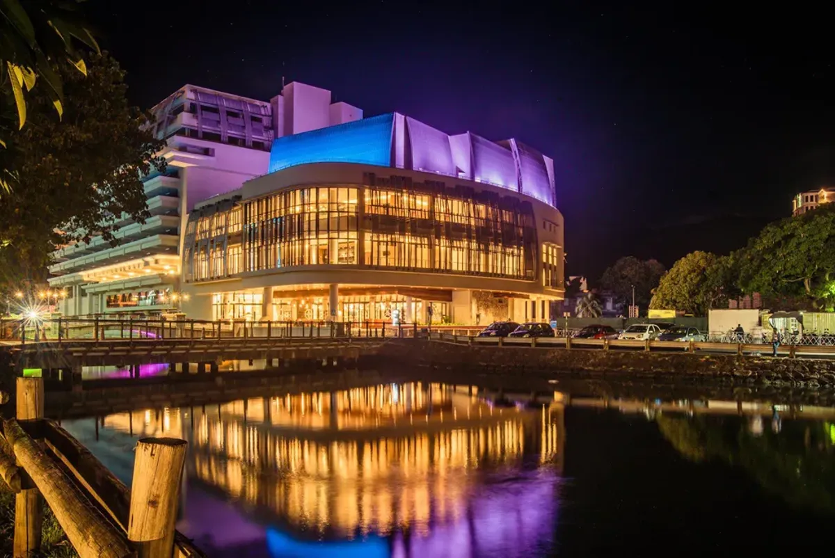 A building with a pool in front of it at night.