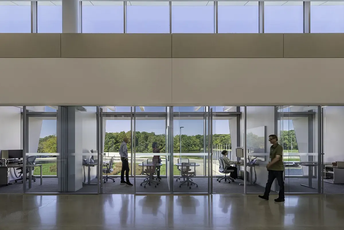 A group of people in a room with glass walls and windows.
