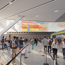 A group in line for airport security with digital display of New York City skyline above