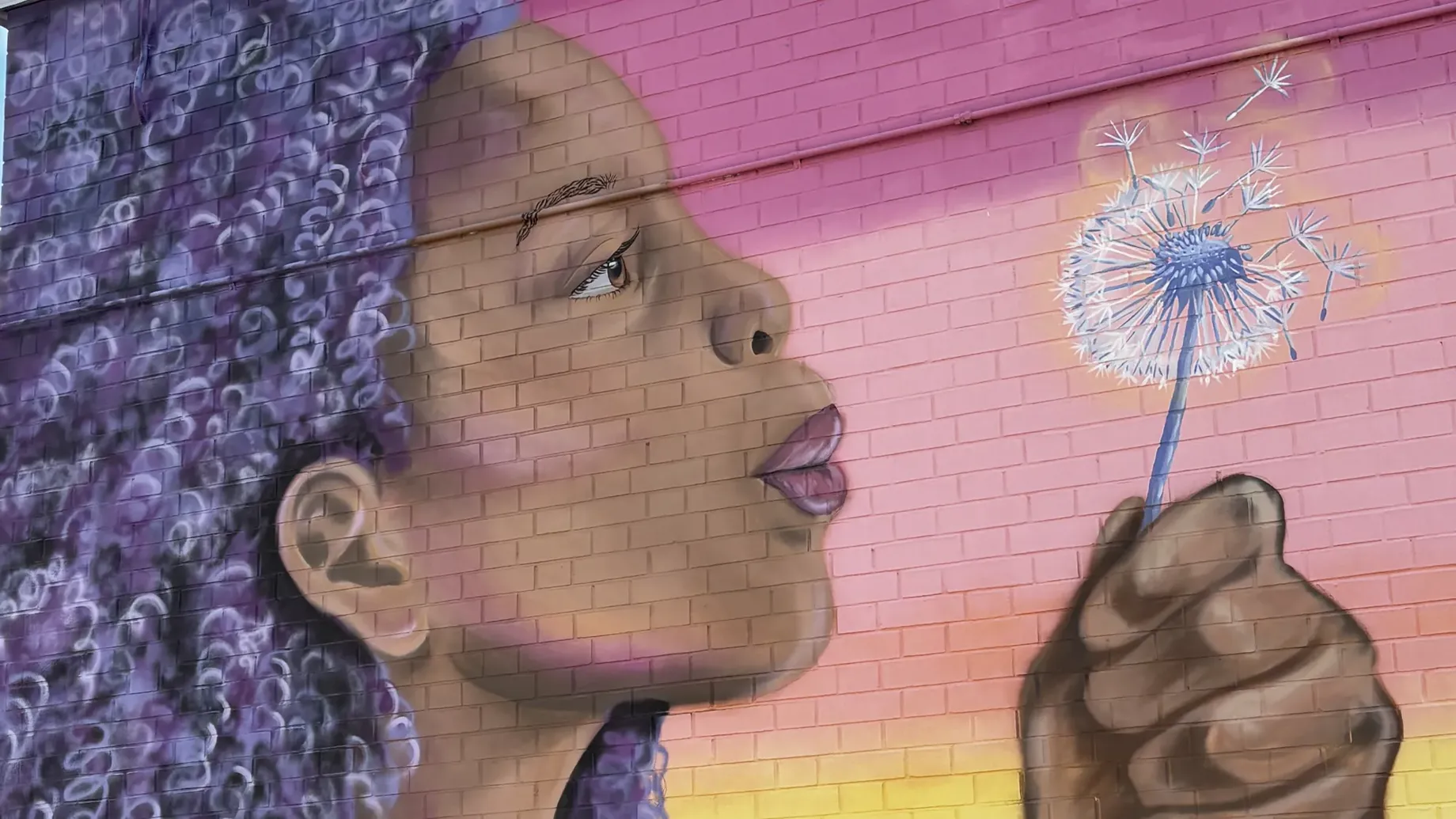 A mural of a woman blowing a dandelion