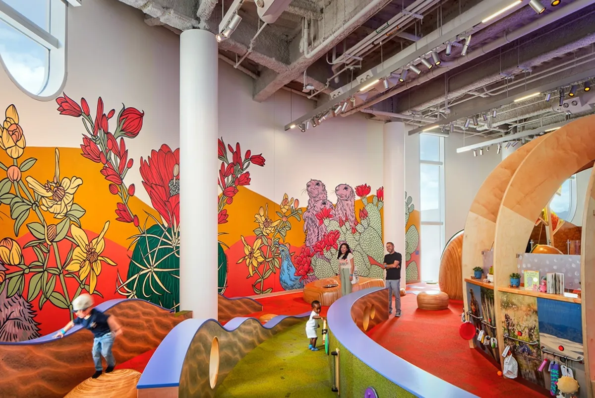 A colorful hands-on exhibition room with a wall mural