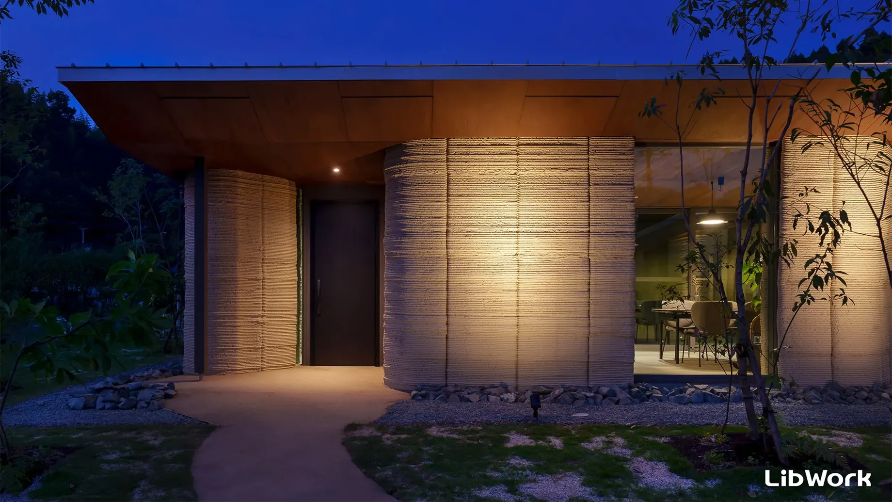A house with a garage and a patio with trees and a light.