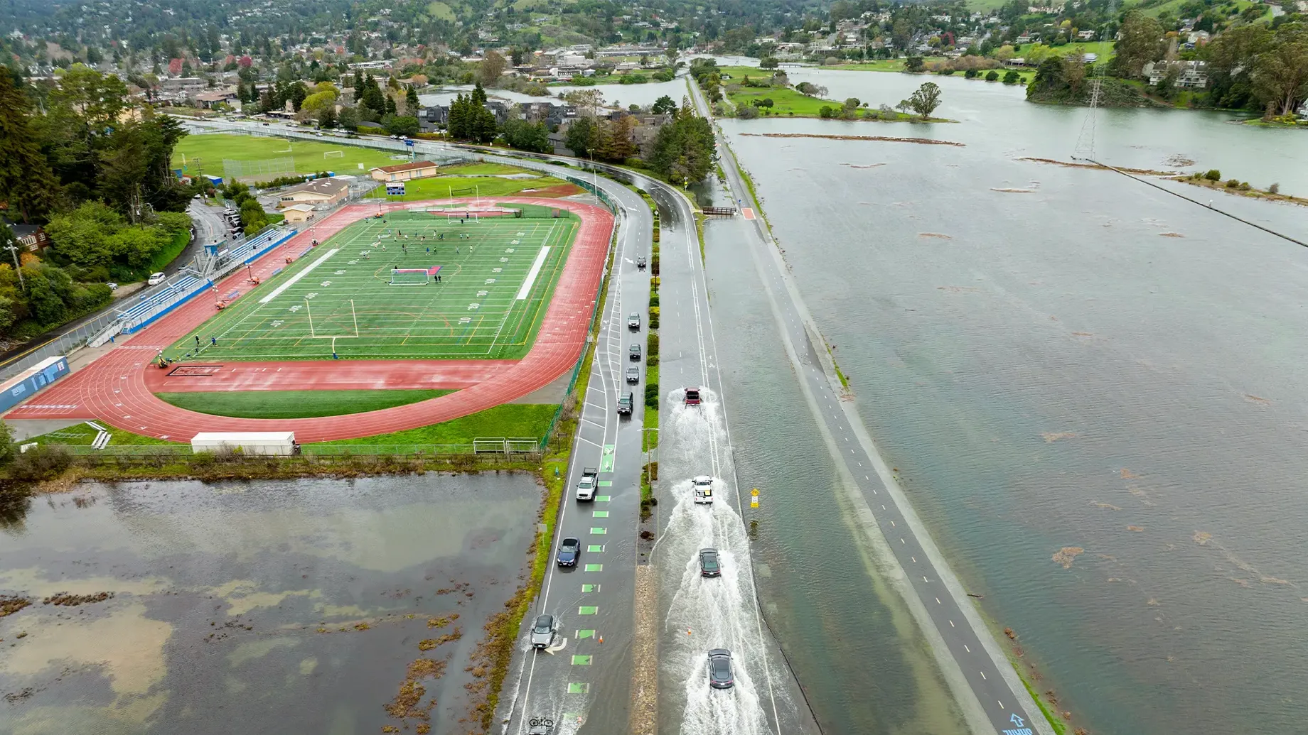 A high angle view of a flooded road with cars traveling through