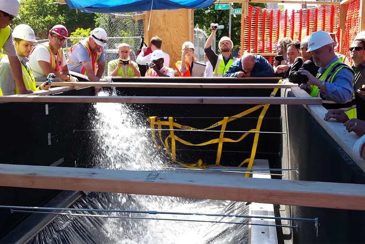 A group of people in safety vests looking at a water fountain.