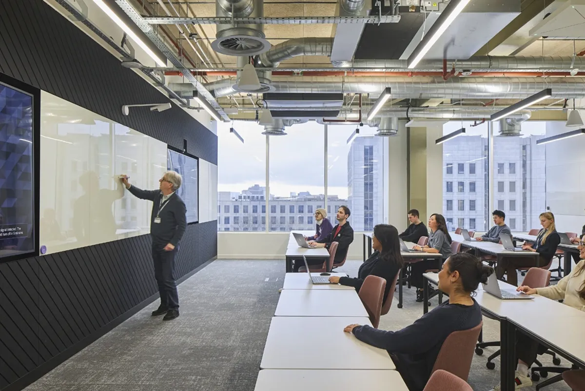 A person standing in front of a group of people sitting at tables.