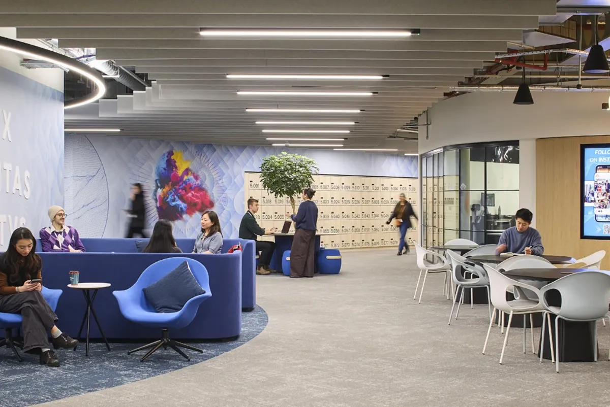 A group of people sitting in a room with tables and chairs.