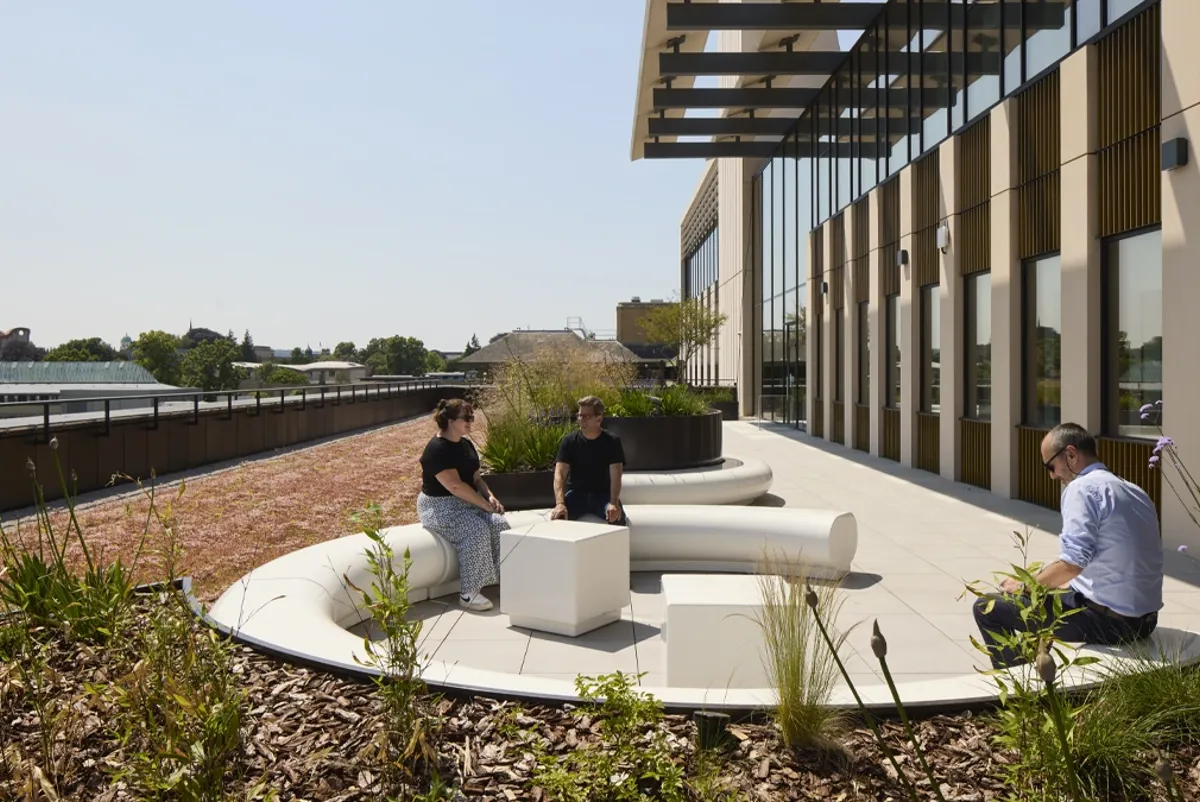 A group of people sitting on a white couch outside a building.