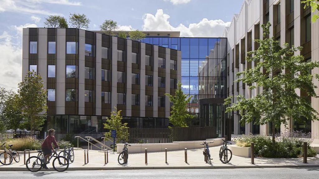 A group of people riding bikes on a sidewalk next to a building.