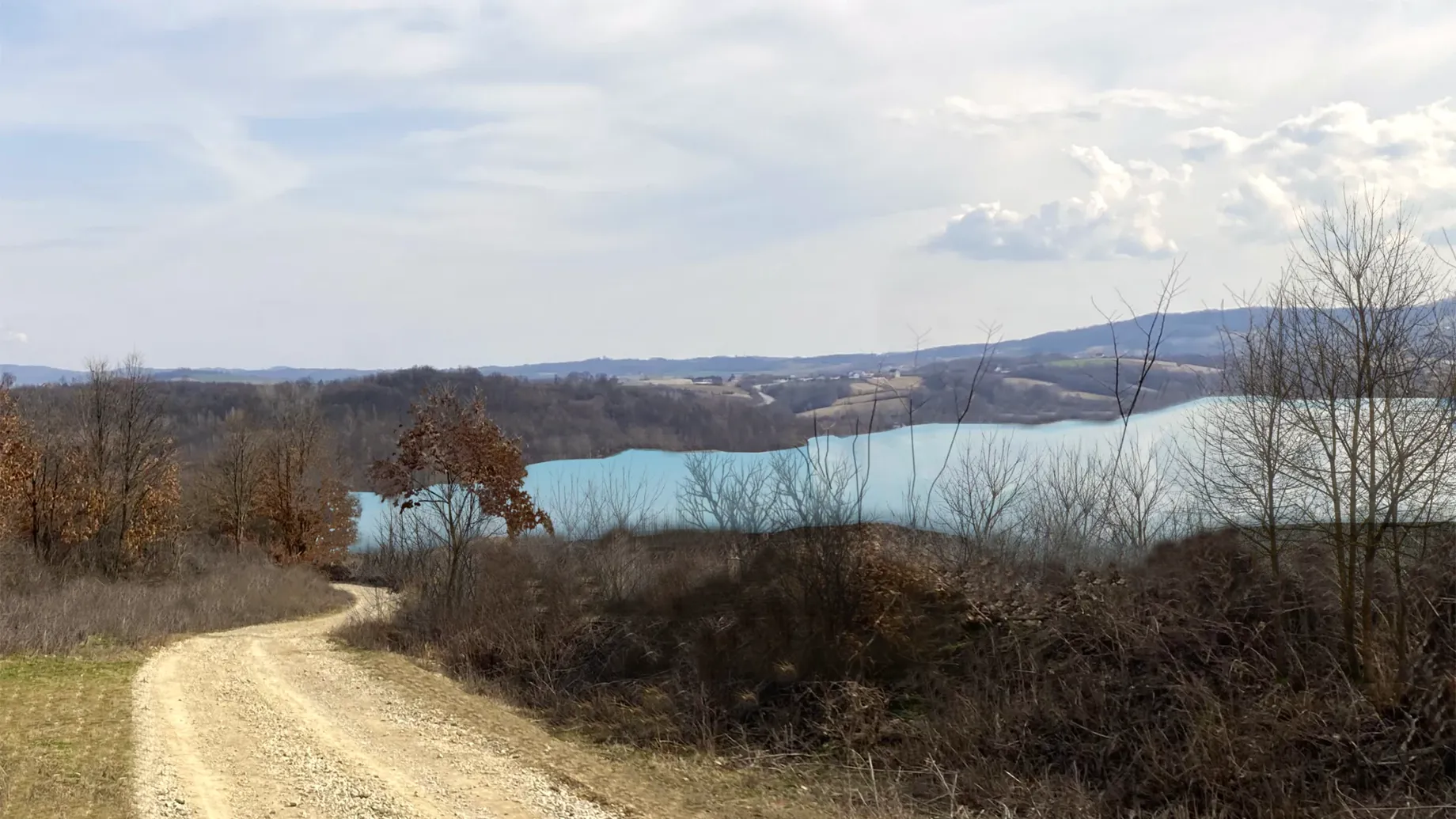 A dirt road next to a body of water.
