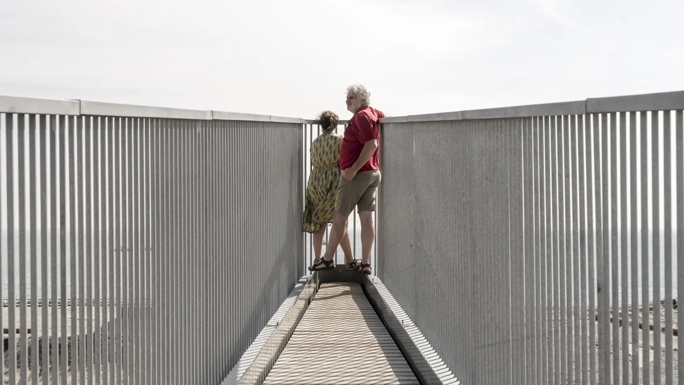 A man and woman standing at the tip of a bridge.