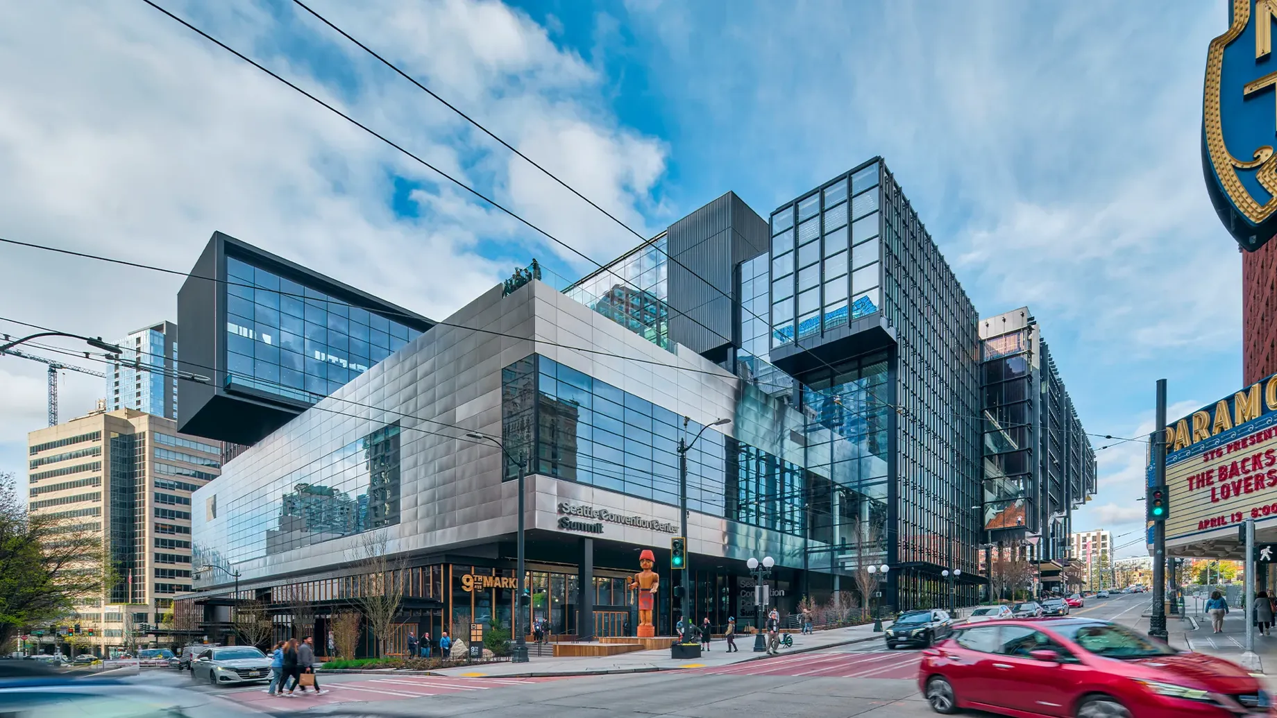 A large glass building with a street and cars in front.