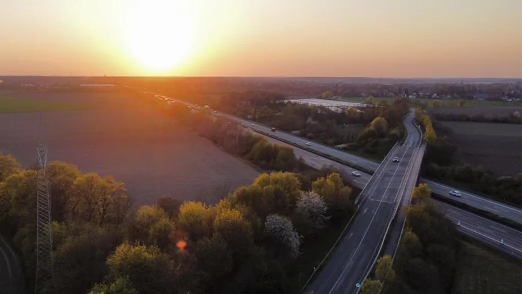 A highway with trees and a sunset.