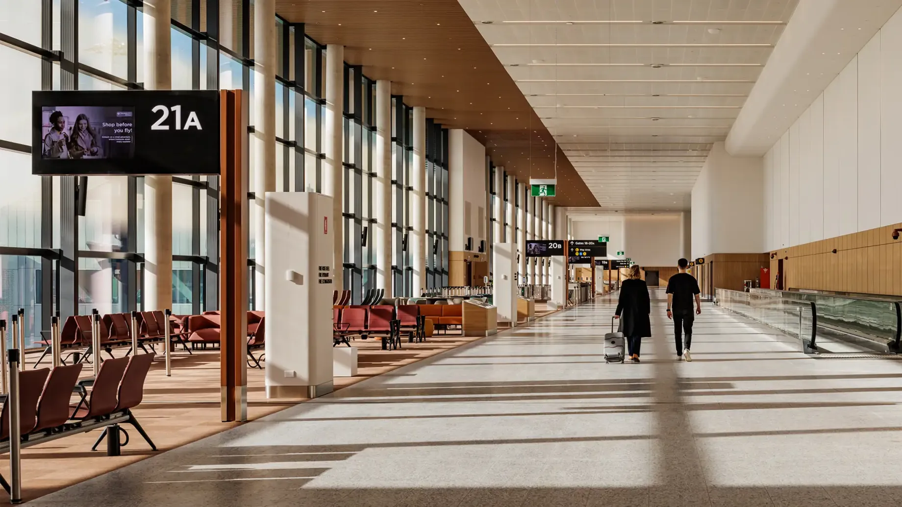 A couple of people walking past gate lounges inside Western Sydney International airport terminal